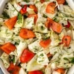 A chopped cabbage salad with red pepper, dill, and peppercorns.