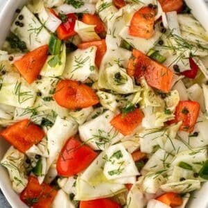 A chopped cabbage salad with red pepper, dill, and peppercorns.