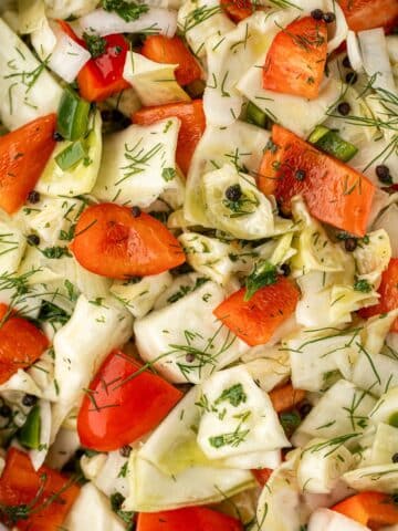 A chopped cabbage salad with red pepper, dill, and peppercorns.