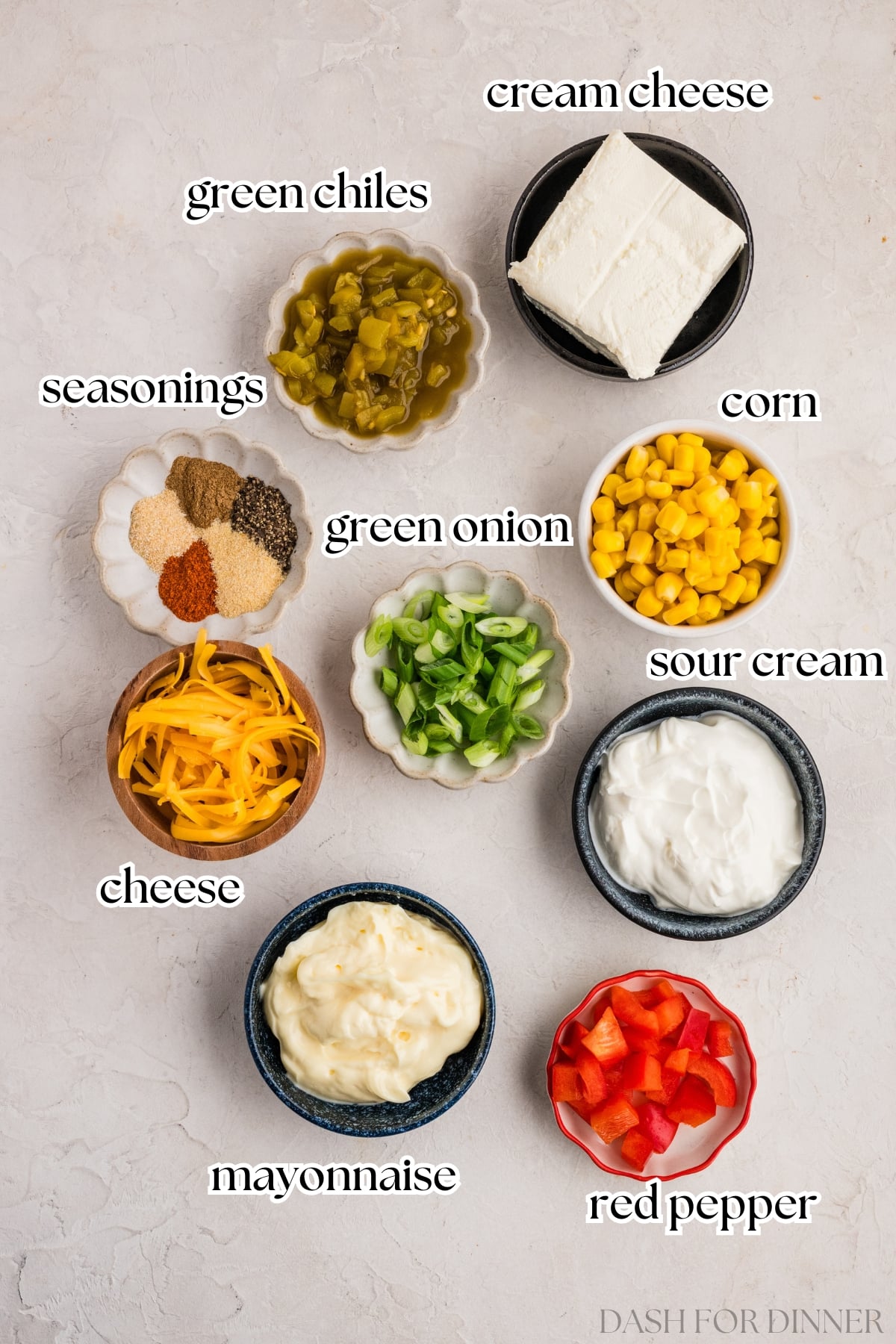 The ingredients needed to make corn dip, including cream cheese, corn kernels, green onion, and mayo.