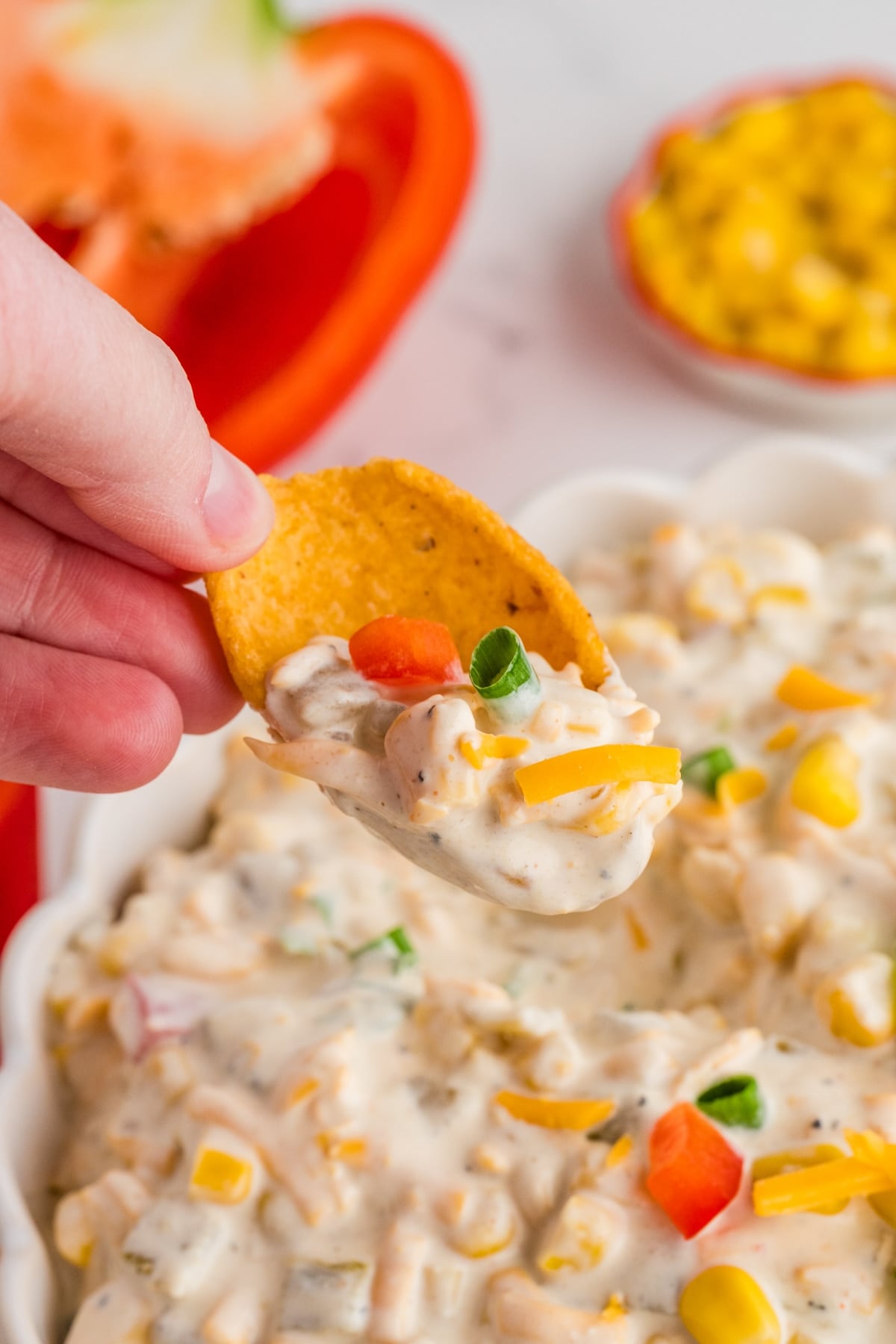 Dipping a frito corn chip into a bowl of corn dip.