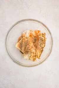 A bowl with cream cheese, sour cream, mayo, and seasonings, ready to be mixed.