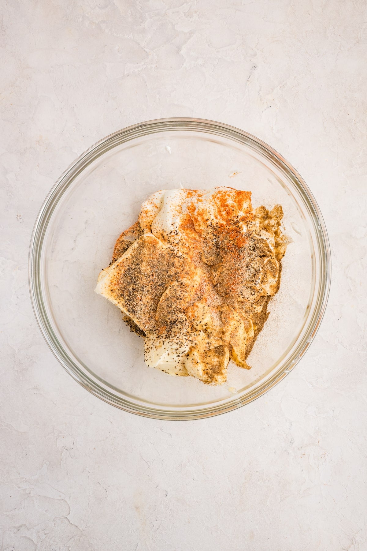 A bowl with cream cheese, sour cream, mayo, and seasonings, ready to be mixed.