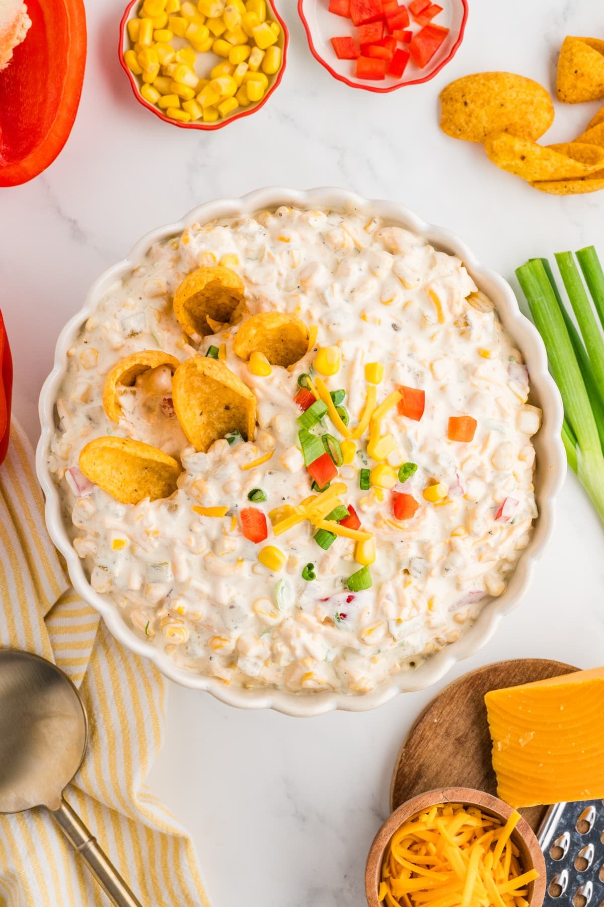 A bowl of creamy corn dip with fritos dipped into the side.