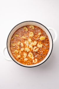 Adding tortellini to a soup pot with a brothy base.