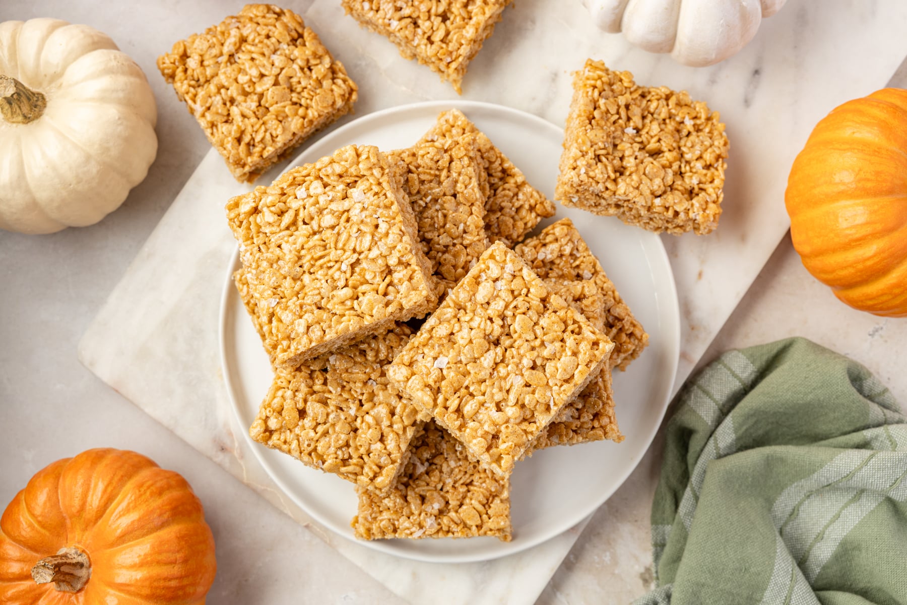 A white plate filled with pumpkin rice krispie treats.