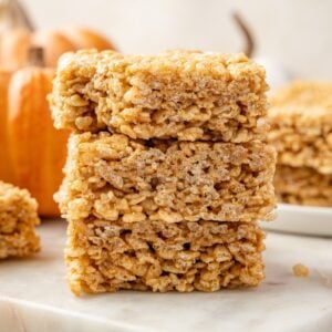 A stack of pumpkin rice krispie treats on a marble surface.