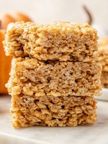 A stack of pumpkin rice krispie treats on a marble surface.